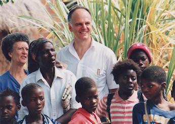 David Nabarro standing in a group of children and a few adults in Mozambique.